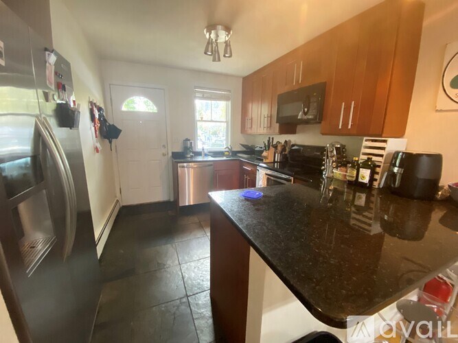 A kitchen with a black granite counter top and wooden cabinets.