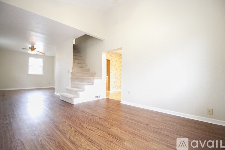 A room with wooden floors and a staircase leading to another room.