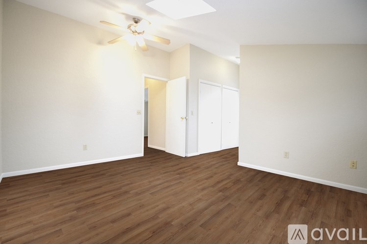 A room with a ceiling fan and wooden flooring.