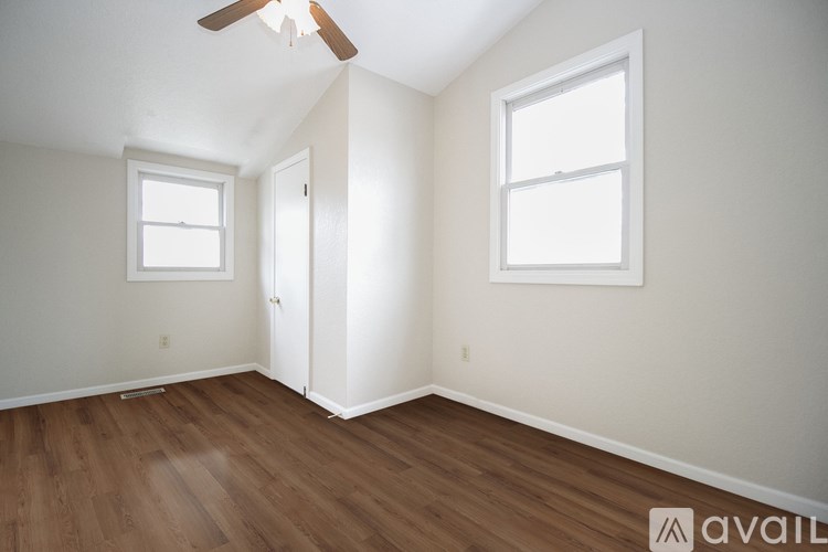 A room with a ceiling fan and two windows.