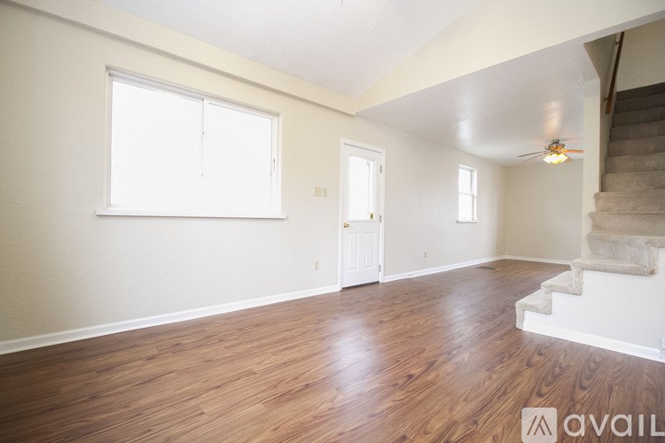 A room with wooden floors and a staircase on the right side.