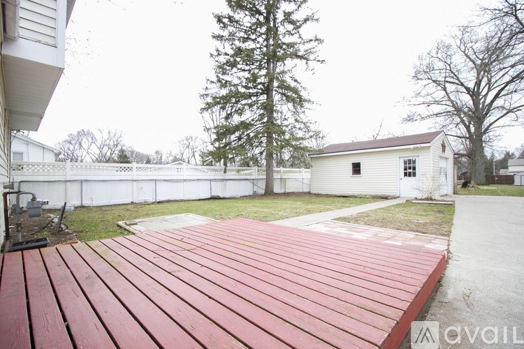 A wooden deck in front of a white house.