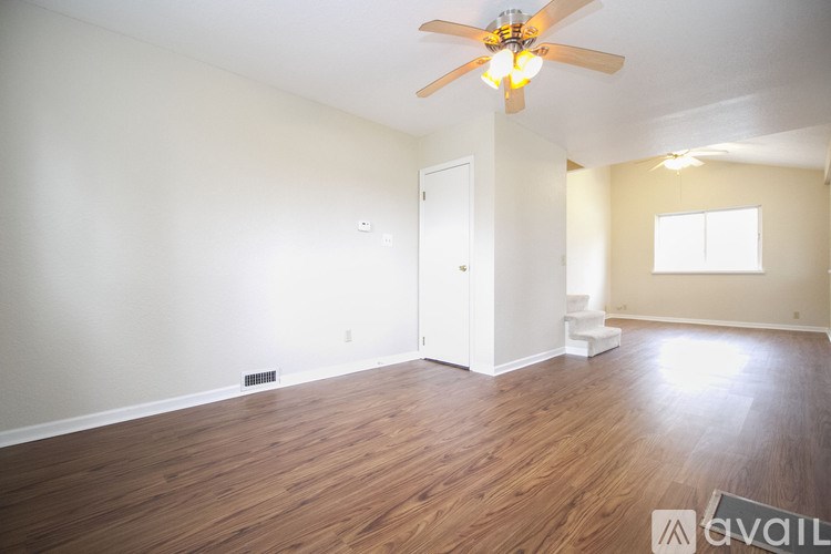 A room with a ceiling fan and wooden flooring.
