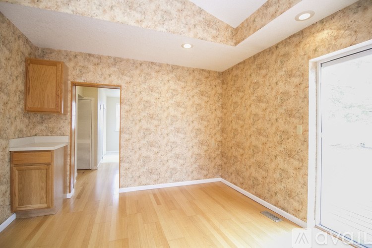 A room with wooden floors and a wallpapered wall with a skylight.