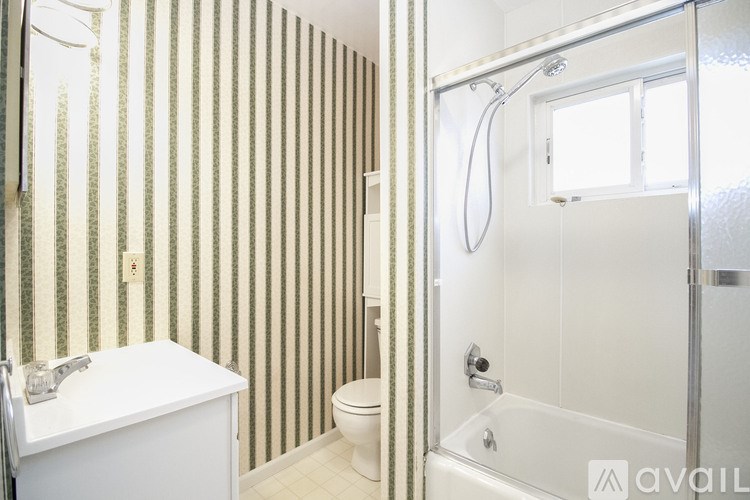 A bathroom with a toilet, sink, and striped wallpaper.