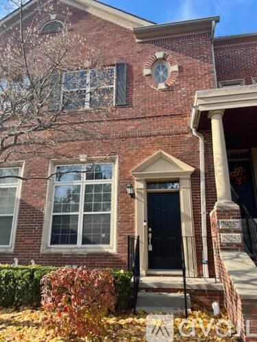 A brick house with a black door and a window with white trim.