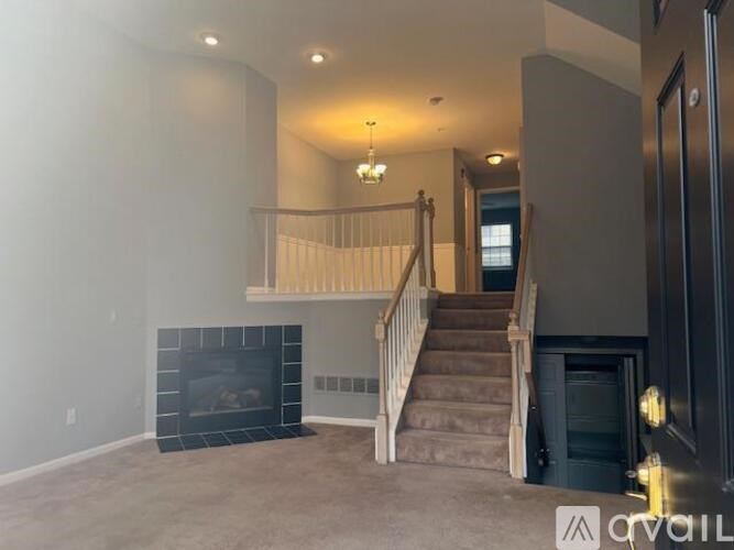 A living room with a fireplace and stairs leading to another room.