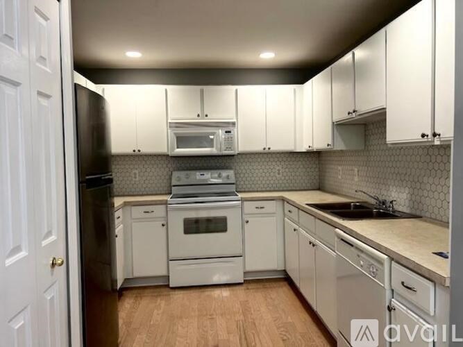 A kitchen with white cabinets and appliances.