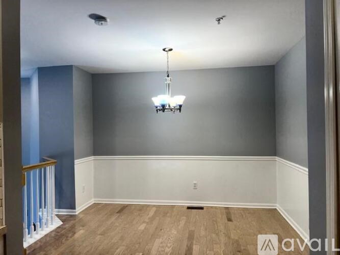 A room with a wooden floor and a chandelier hanging from the ceiling.