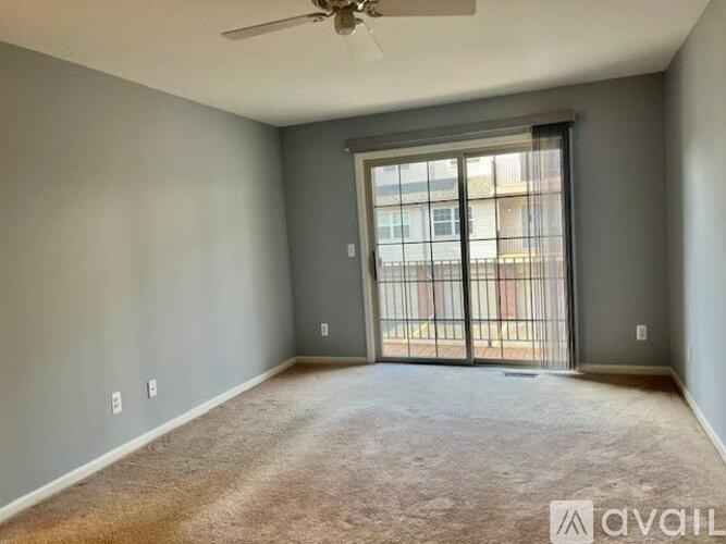 A room with a carpeted floor and a ceiling fan.