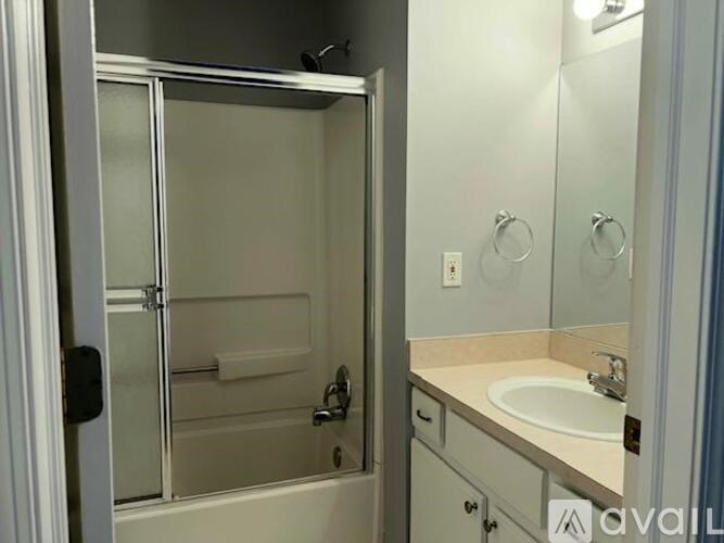 A bathroom with a sink, mirror, and shower.
