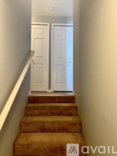 A hallway with a staircase and two doors.