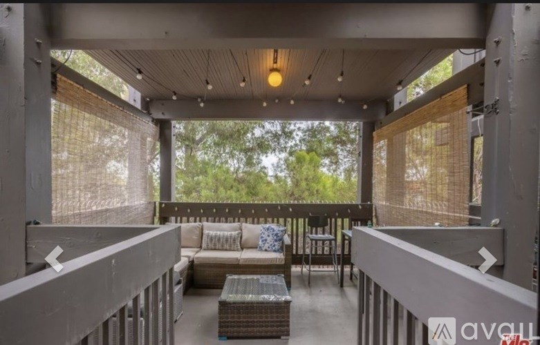 A patio with a couch and chairs is surrounded by a metal railing.