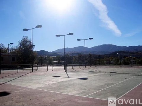 Tennis court with sun shining and mountains in the background.