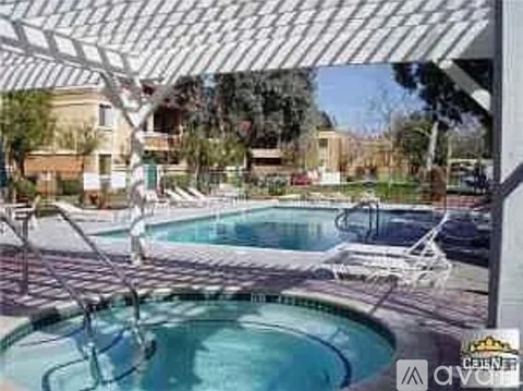 A pool with a hot tub and sun loungers under a white canopy.