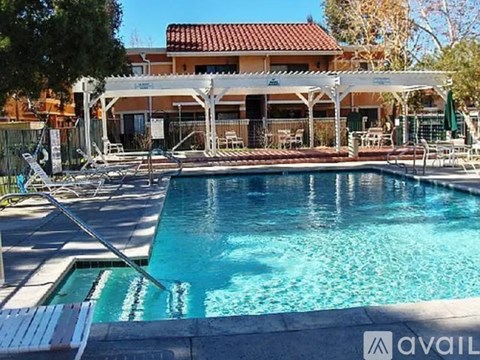 A pool with a white canopy and a building in the background.