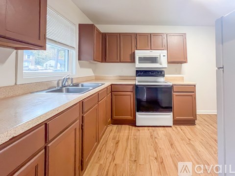 A kitchen with brown cabinets and a white microwave above the stove.