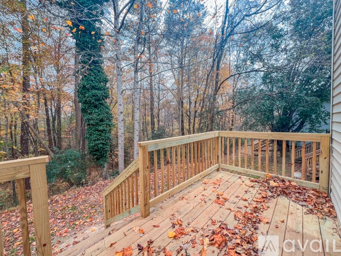 A wooden deck with fallen leaves on it surrounded by trees.