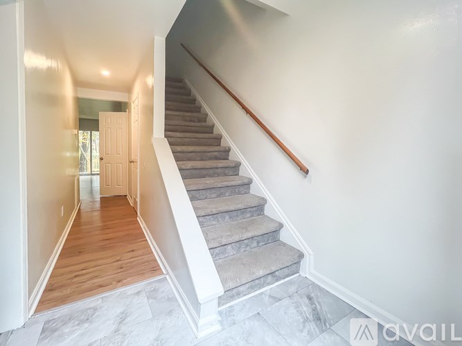 A staircase with a wooden handrail and white walls.
