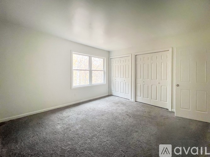 A room with a carpeted floor, a window, and a door.