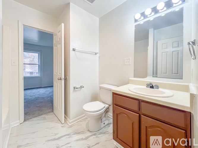 A bathroom with a toilet, sink, and mirror.