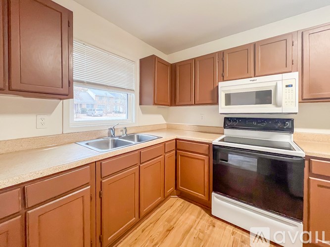 A kitchen with brown cabinets and a white microwave above the stove.