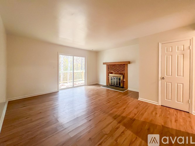 A room with wooden floors and a fireplace with a door on the right side.