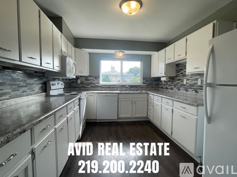 A kitchen with white cabinets and a stone backsplash is for sale.