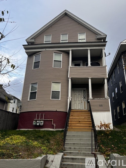 A two-story house with a red front door and stairs leading up to it.
