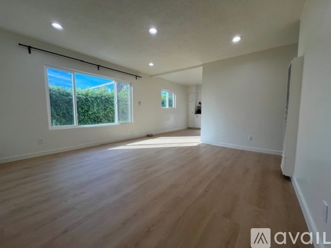 A spacious room with wooden flooring and a large window.