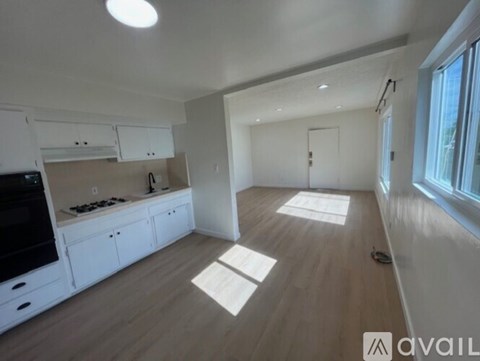 A spacious kitchen with white cabinets and a flat-screen TV.