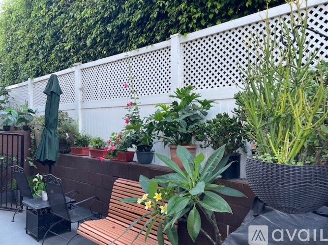 A patio with a white fence and a variety of plants.