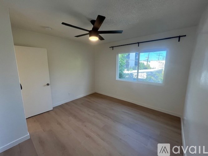 A room with a ceiling fan and a window overlooking a street.