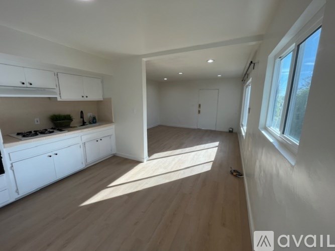 A kitchen with white cabinets and a wooden floor.