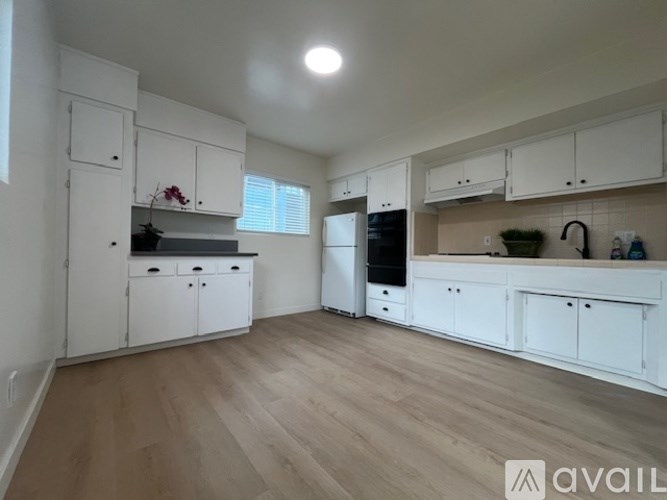 A kitchen with white cabinets and a wooden floor.