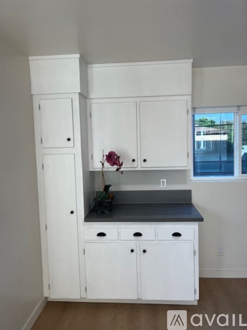 A kitchen with white cabinets and a black countertop.