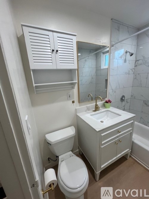 A white bathroom with a toilet, sink, and a cabinet above it.