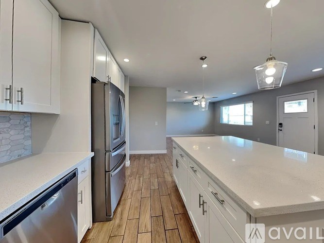 A kitchen with white cabinets and a wooden floor.