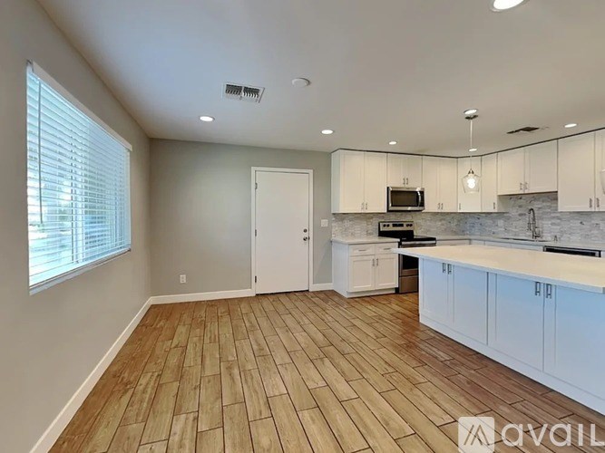 A kitchen with white cabinets and a wooden floor.