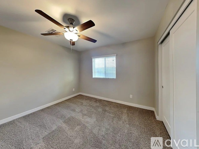 A room with a ceiling fan and carpeted floor.