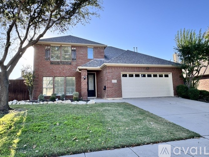 A red brick house with a white garage door and a tree in front.