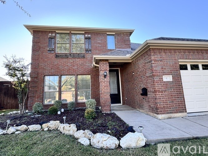A brick house with a white garage door and a stone wall in front.