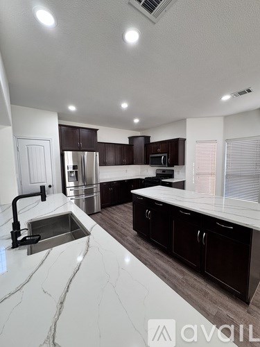 A modern kitchen with a marble countertop and stainless steel appliances.