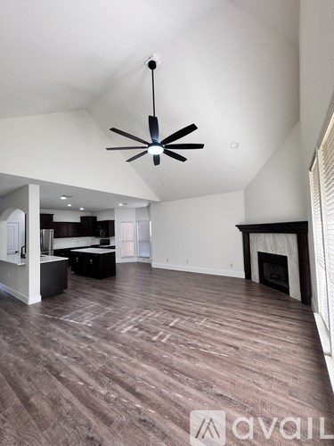 A spacious room with a ceiling fan and a fireplace.