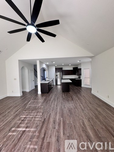 A spacious room with a ceiling fan and wooden flooring.