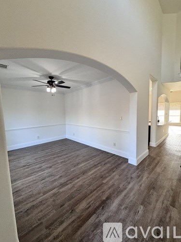 A room with a ceiling fan and wood flooring.