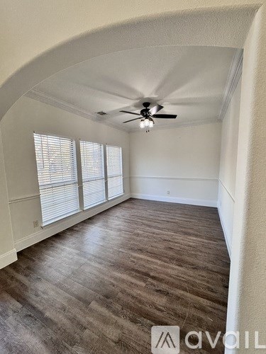 A room with a ceiling fan and wooden flooring.