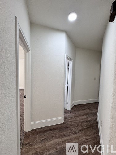 A hallway with a carpeted floor and white walls.