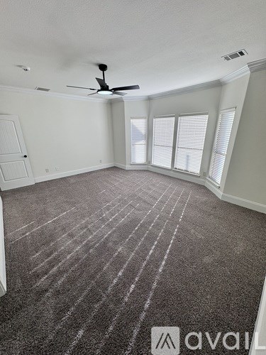 A room with a carpeted floor and a ceiling fan.
