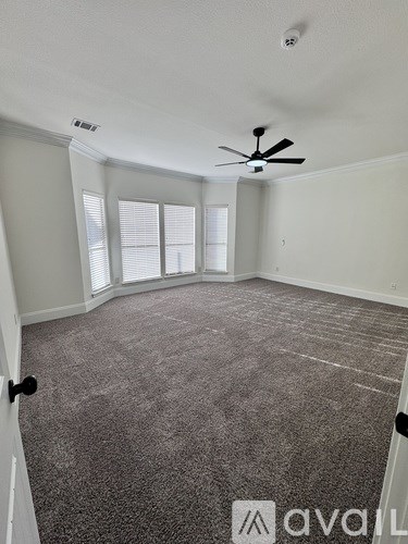 A room with a carpeted floor and a ceiling fan.